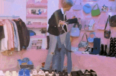 a man is standing in a closet full of clothes and shoes