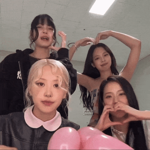 a group of young women are making a heart shape with their fingers