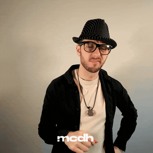 a man wearing a hat and glasses is standing in front of a mcdh sign