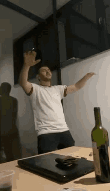 a man is standing in front of a table with a bottle of wine on it