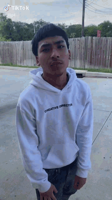 a man wearing a white hoodie that says creative director on it
