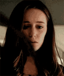a close up of a woman 's face with a sad look on her face and a black background .