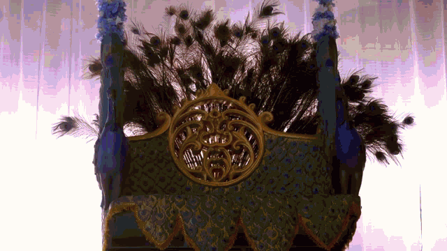 a crown with peacock feathers on it and a gold emblem