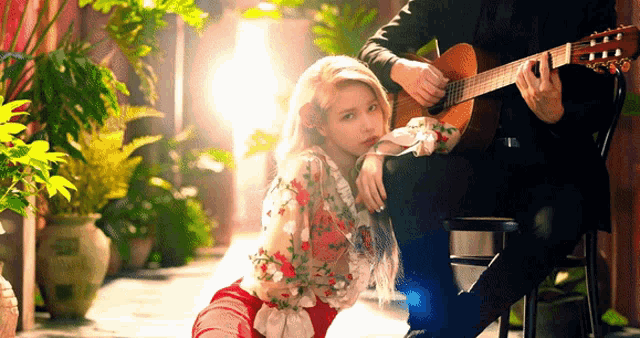 a man is playing a guitar next to a woman who is kneeling down