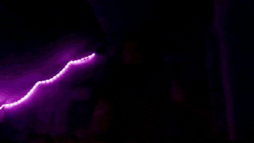 a person standing in a dark room with a green light behind them