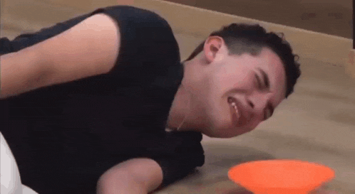 a young man is laying on the floor with his head on a bowl .