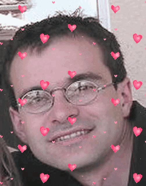 a man with glasses is surrounded by pink hearts on his face