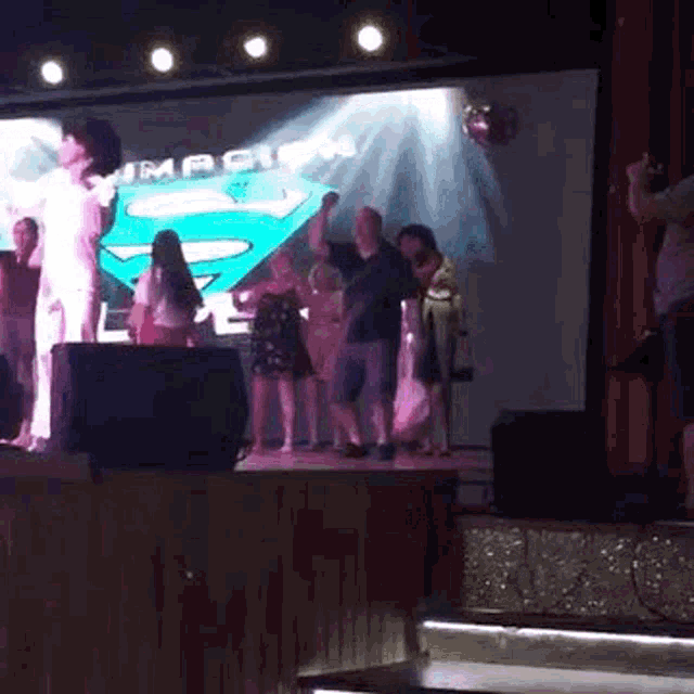 a group of people are dancing on a stage in front of a screen that says " impact "