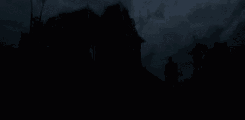 a silhouette of a person standing in front of a haunted house at night