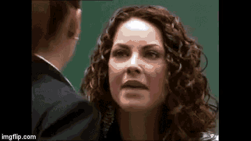 a woman with curly hair is standing next to a man in a suit .