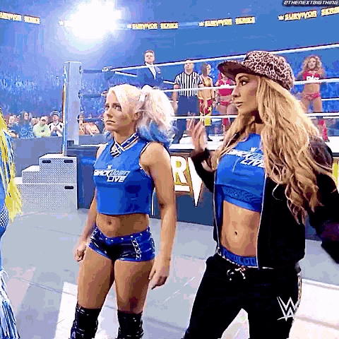 two women are standing in a wrestling ring and one of them is wearing a blue shirt that says ' back light lite '