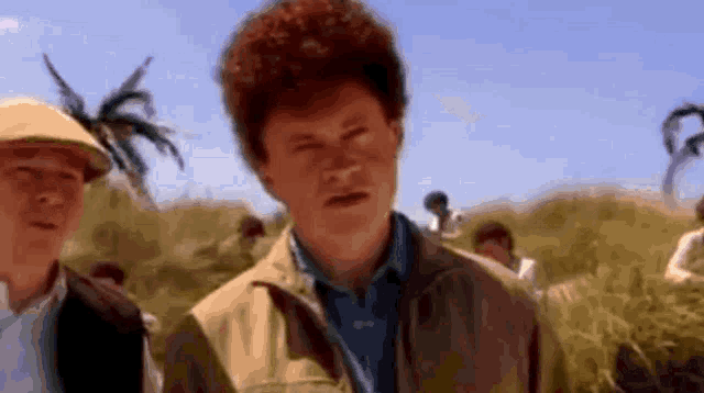 a man with a red haircut is standing in a field with a group of people .