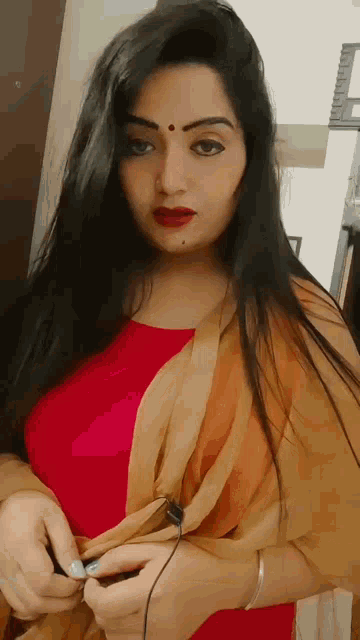 a woman in a red dress is holding a pair of headphones .