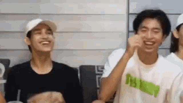a group of young men are sitting next to each other in a room laughing and making funny faces .