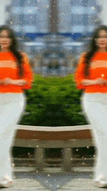 a woman in an orange shirt is standing in front of a mirror