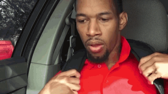 a man in a red polo shirt is sitting in a car