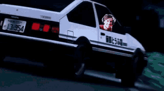 a man is driving a car with headphones on and a license plate that says 13854 .
