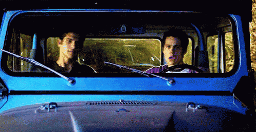 two men are driving a blue jeep and one of them has the number 6 on the windshield