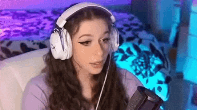 a girl wearing headphones and a microphone is sitting in front of a microphone .