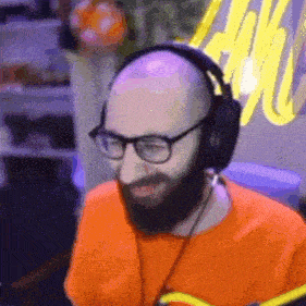 a man with a beard and glasses is wearing headphones and an orange shirt .