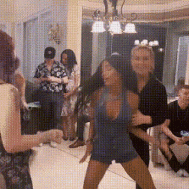 a woman in a blue tank top is dancing in a room