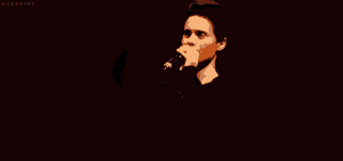 a man is singing into a microphone in a dark room and says `` fuck them '' .