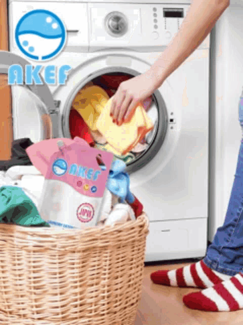 a person is putting clothes in a washing machine with a bag of aker on the floor
