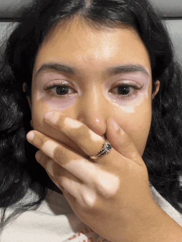 a woman with a ring on her finger covering her face