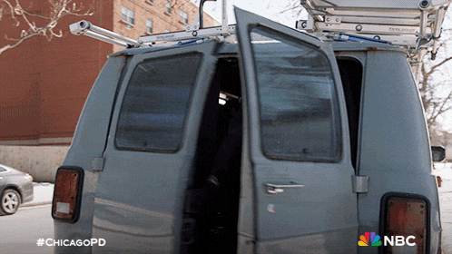 a gray van with a ladder on top of it and a nbc logo on the bottom right