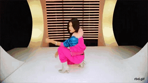 a woman in a pink jumpsuit is squatting on a white surface ..