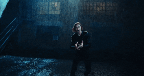 a man in a leather jacket is kneeling in the rain