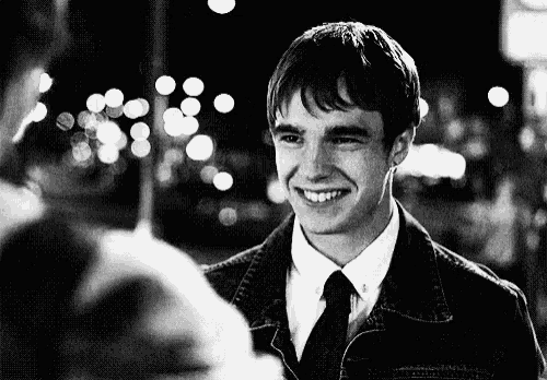 a man in a denim jacket and tie is smiling at a woman .
