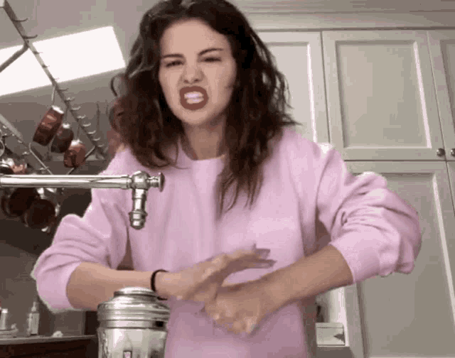 a woman wearing a pink sweater is washing her hands