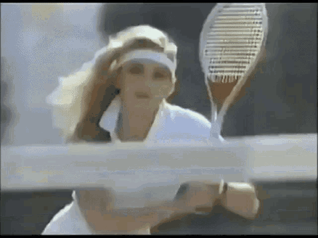 a woman is holding a tennis racquet behind a net