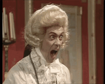 a man wearing a wig and a white shirt is making a surprised face .