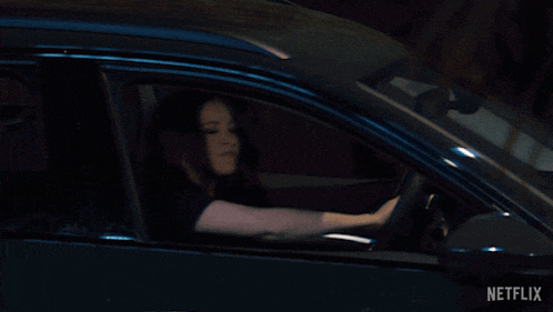 a woman is driving a car with netflix written on the bottom right