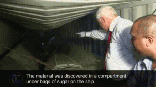 two men are looking into a container with the words " the material was discovered in a compartment under bags of sugar on the ship "