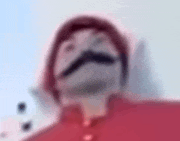 a blurry picture of a man with a mustache wearing a red shirt and a hat .