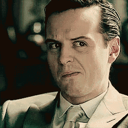 a man in a suit and tie looks at the camera with a serious look on his face