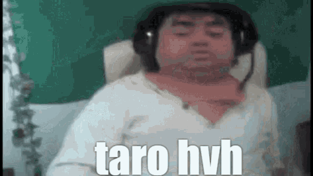 a man wearing headphones and a scarf is sitting on a couch and saying taro hvh .