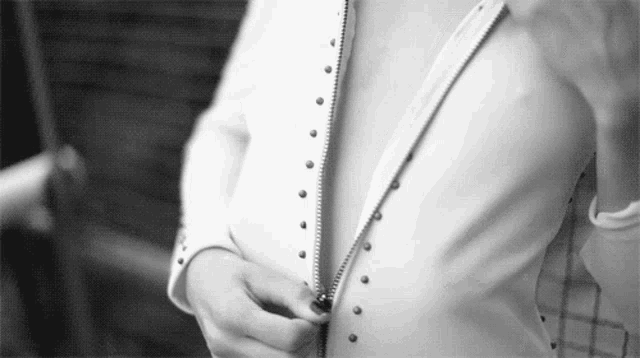 a woman is wearing a white shirt with a zipper on it .