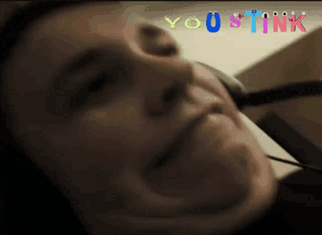 a close up of a person 's face with the words " you stink " in the background