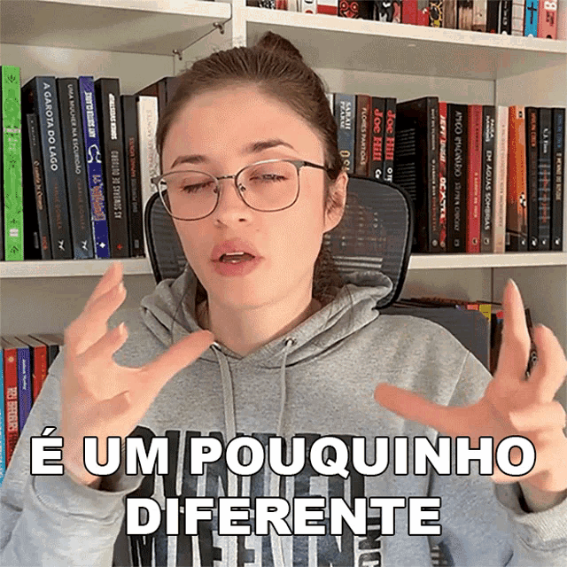 a woman wearing glasses and a gray hoodie says e um pouquinho diferente
