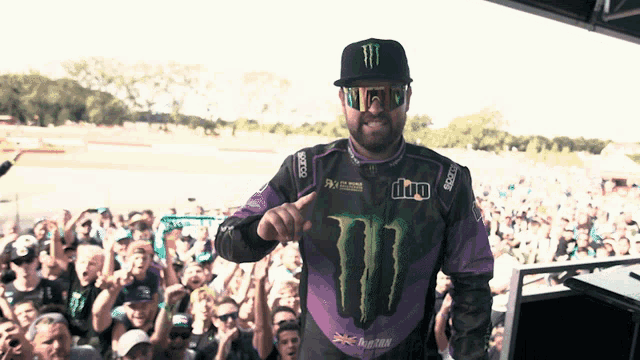 a man wearing a monster shirt and sunglasses stands in front of a crowd