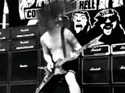 a shirtless man is playing a guitar in front of a wall that says hell on it