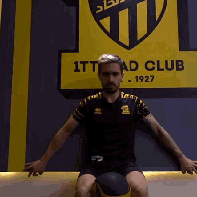a man sitting in front of a sign that says 1tt ad club