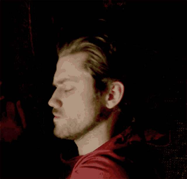 a man with a beard and a red shirt is making a funny face