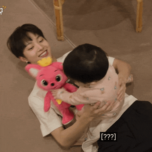 a man holding a baby and a stuffed animal with the letters [ ? ] on the bottom right