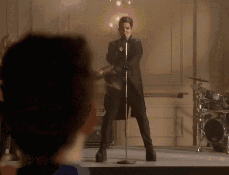 a man is singing into a microphone while standing on a stage