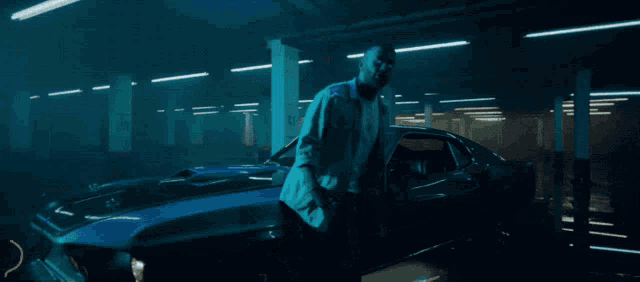 a man is standing next to a car in a parking garage with the number 10 on the wall
